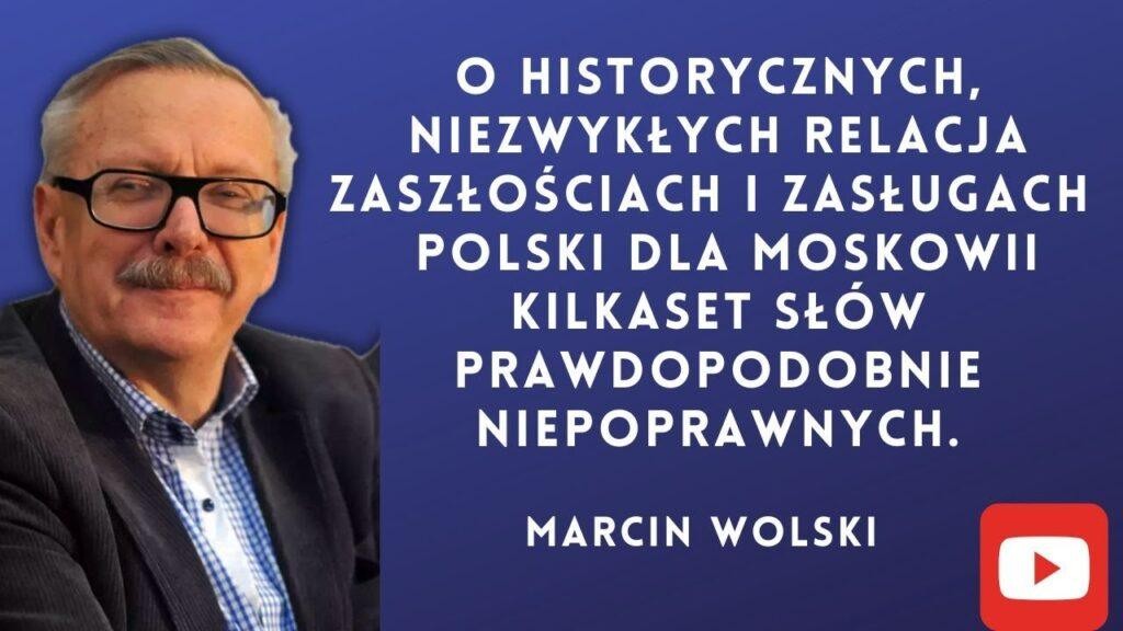 Kompozycja symbolizująca karierę Marcina Wolskiego: stos książek, mikrofon radiowy i pióro, odzwierciedlające jego działalność literacką i radiową.